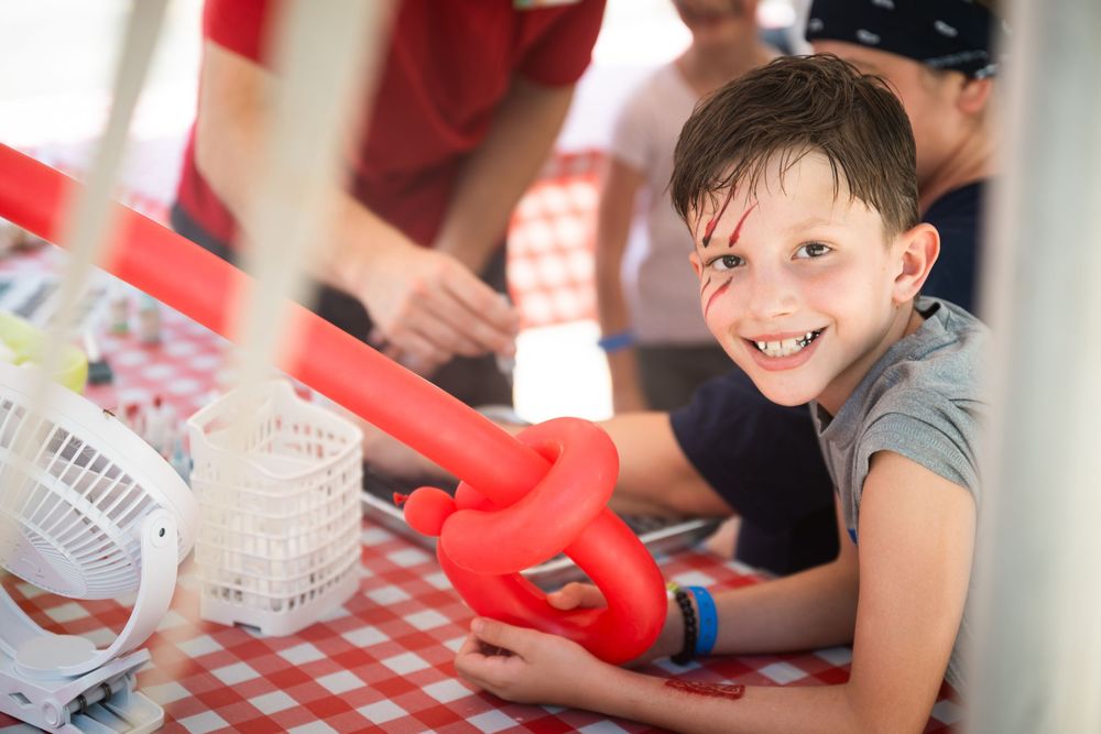 Students engage in hands-on learning activities at desks with red and white checkered tablecloths.