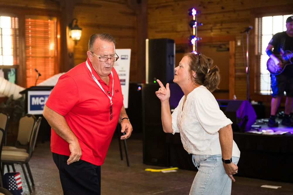 Couples dance together in a dimly lit rustic barn venue with wooden walls and ambient lighting.