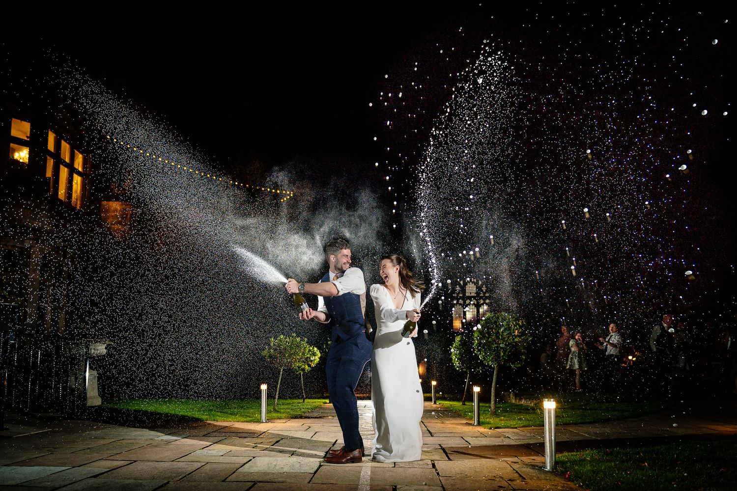 Wedding couple celebrates in a nighttime water fountain display creating a magical silhouette.