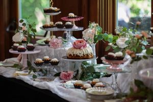 Elegant dessert table with tiered cake stands, cupcakes, and floral decorations at a wedding reception.