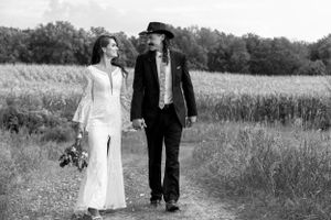 Black and white photo of a bride and groom walking and gazing at each other on a rural path.