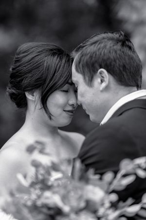 Black and white close-up of a bride and groom touching foreheads tenderly during their wedding day.