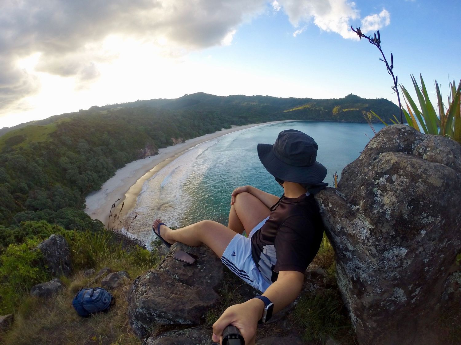 A scenic coastal viewpoint overlooking a pristine crescent beach from rocky cliffs.