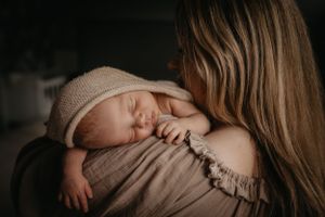 baby op zijn moeder's schouder tijdens newbornshoot
