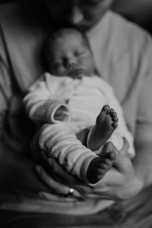 baby bij zijn vader tijdens newbornshoot in zwart-wit