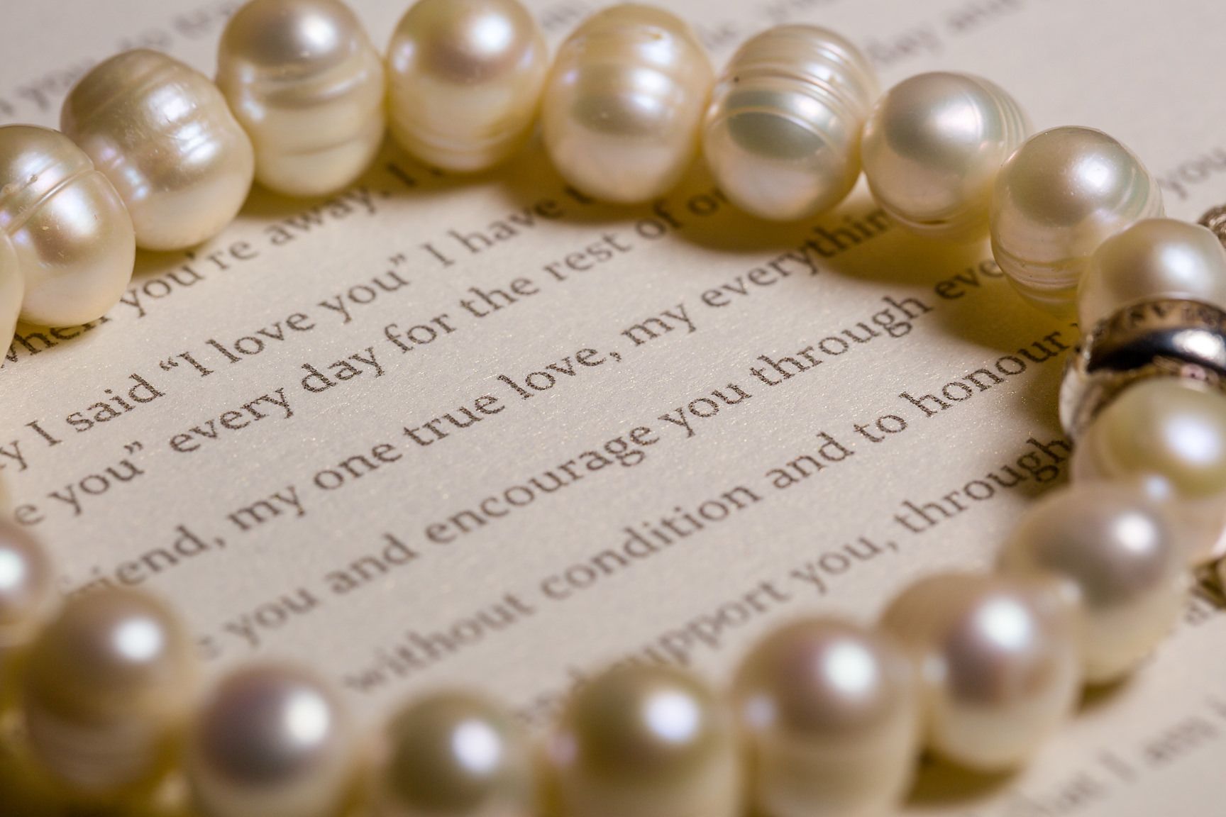 A strand of pearl necklace arranged around text on a white page with romantic writing.