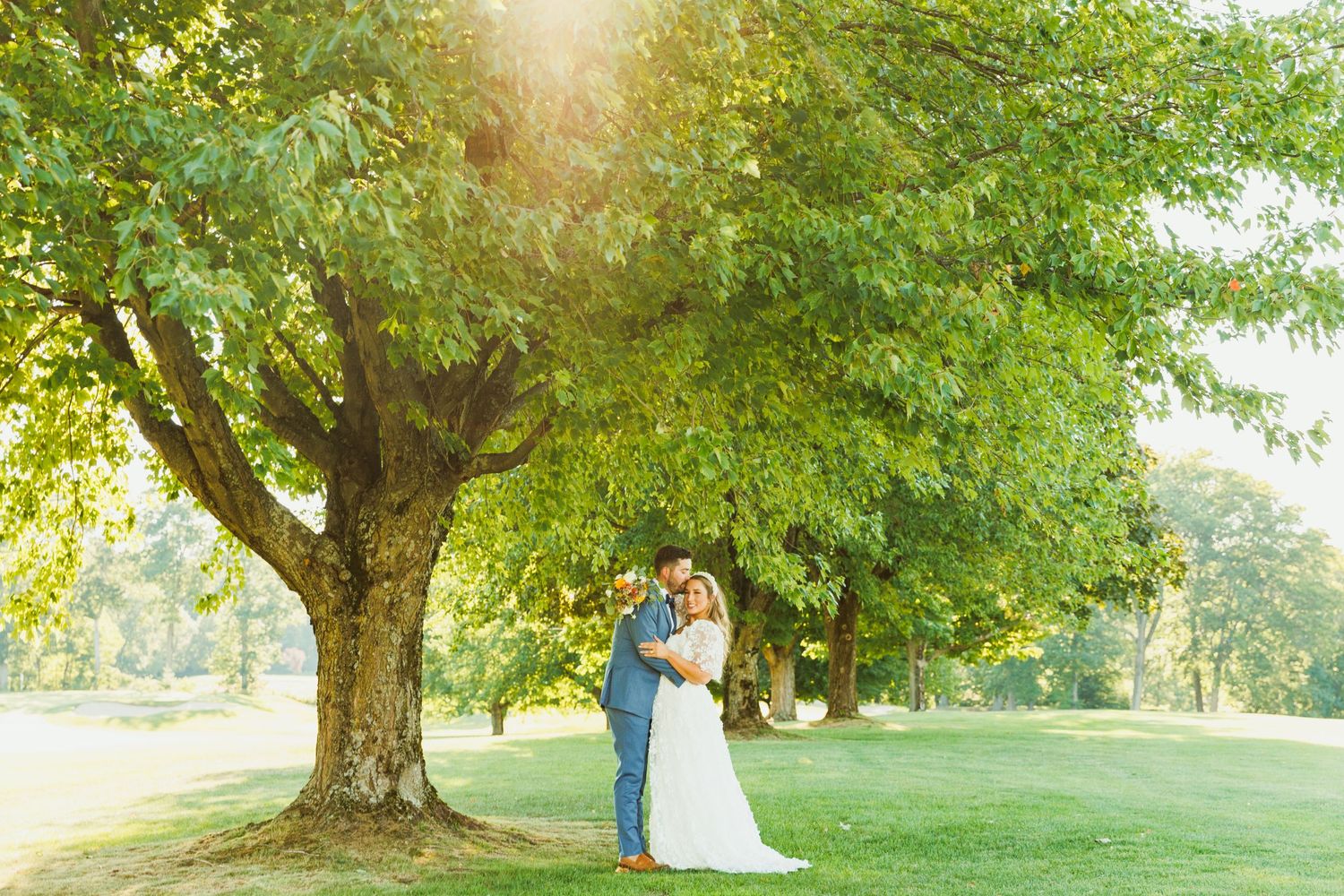 Wedding ceremony and reception venue set among lush green trees at golden hour.