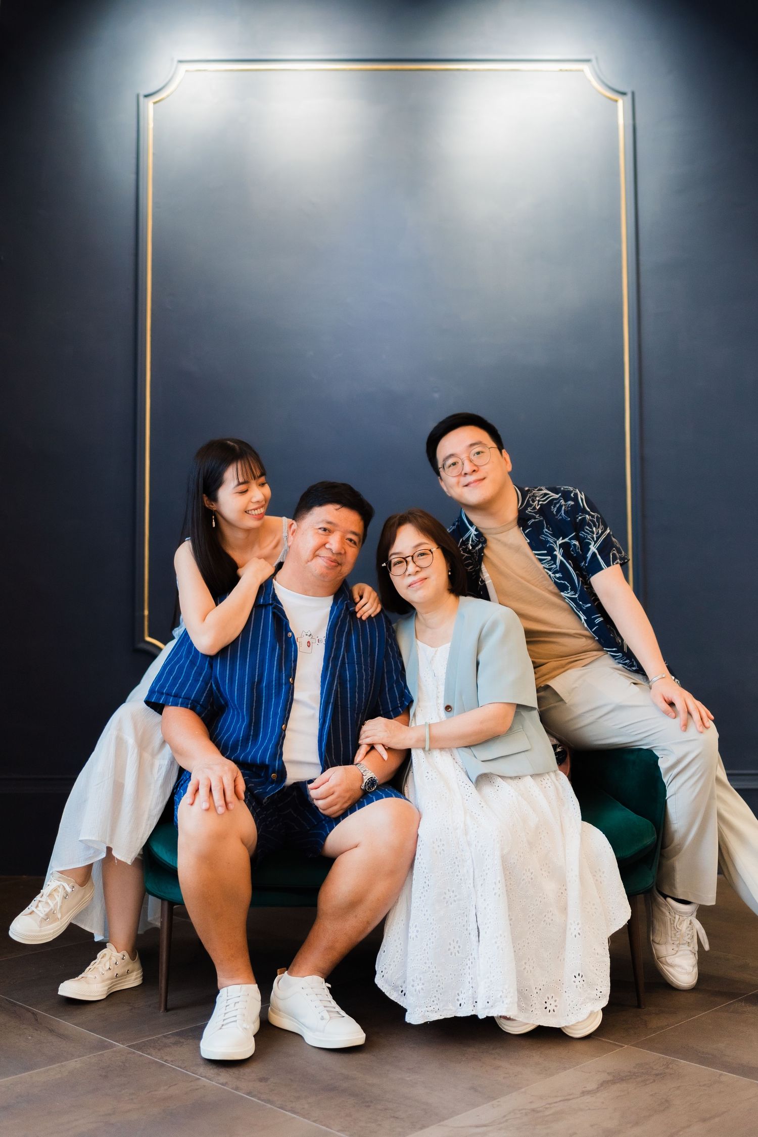 Group portrait of friends posing together against elegant dark wall with gold frame.