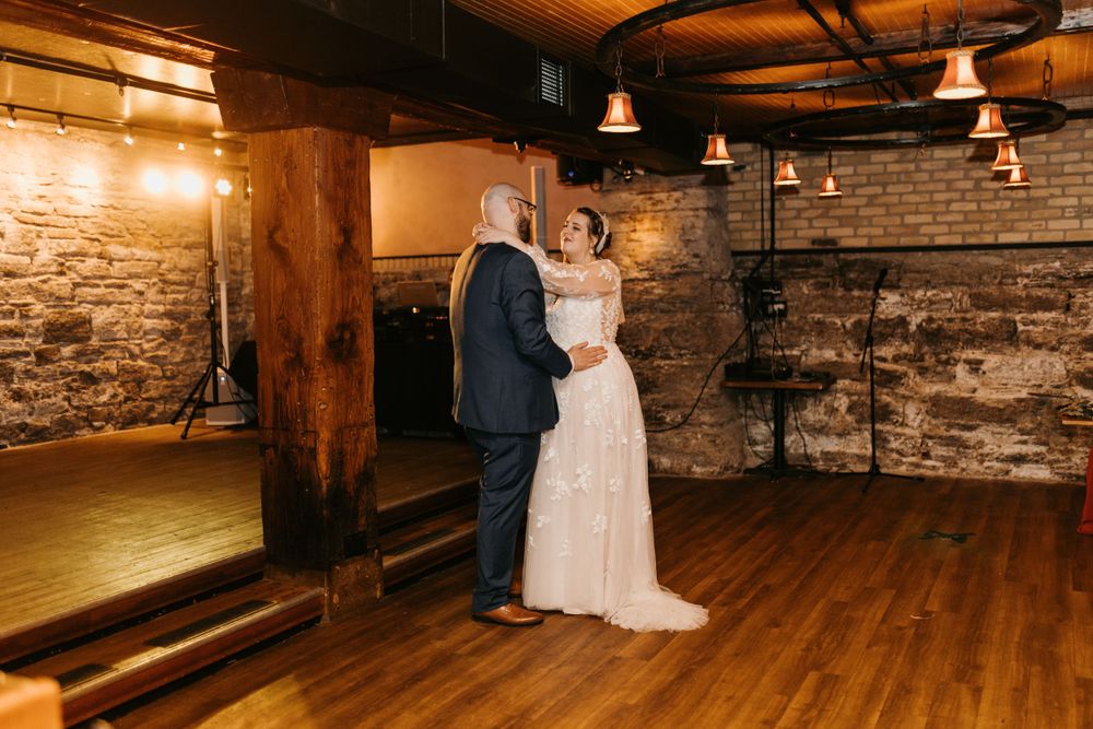Bride and groom sharing an intimate first dance in a warmly lit rustic stone venue.