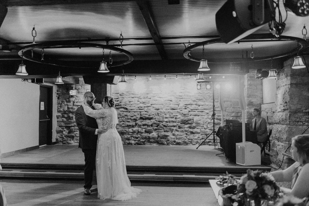 Bride and groom share their first dance in a rustic stone-walled venue during their wedding reception.