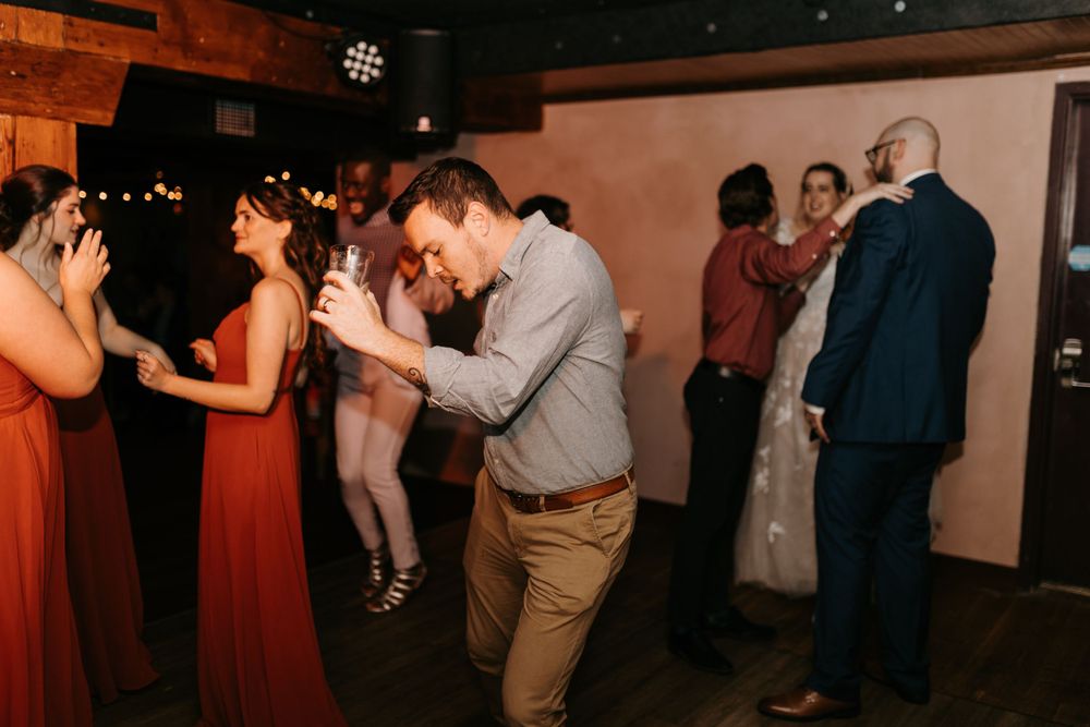 Wedding guests dance and celebrate on the dance floor during a lively wedding reception.