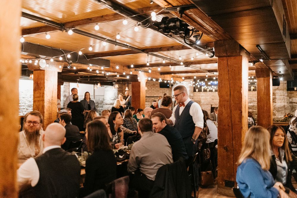 Guests dining at a rustic wedding reception venue with string lights and wooden beams.