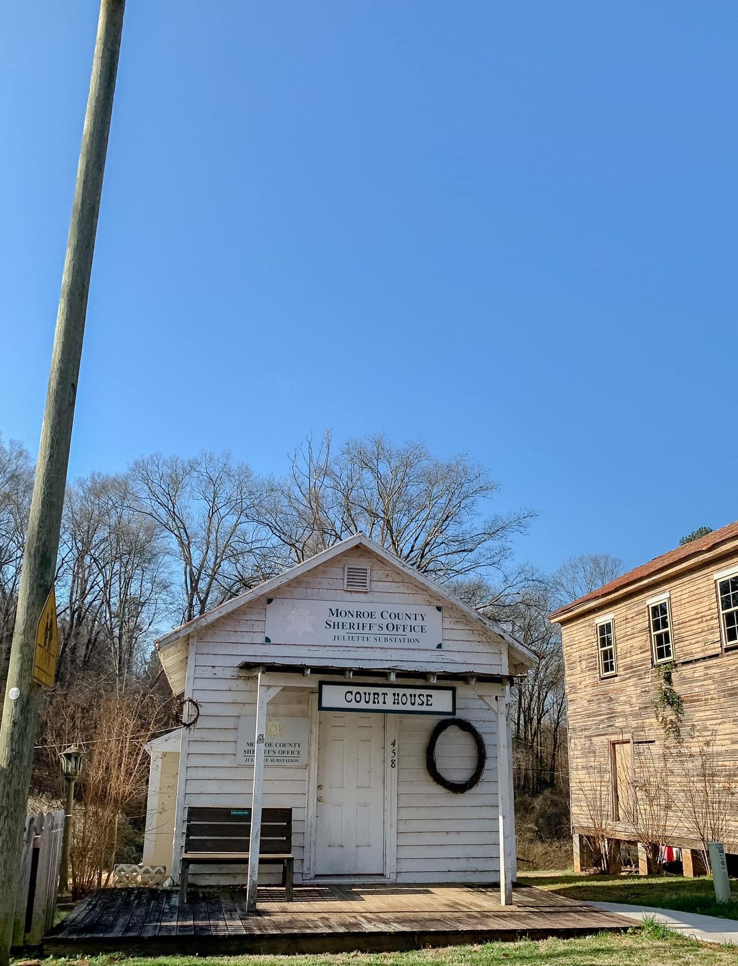 Series of white wooden historic buildings with porches under bare winter trees.