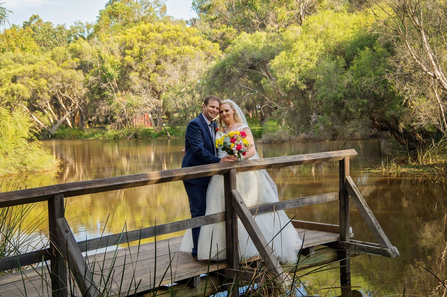 bride and groom posing on bridge at Whiteman park