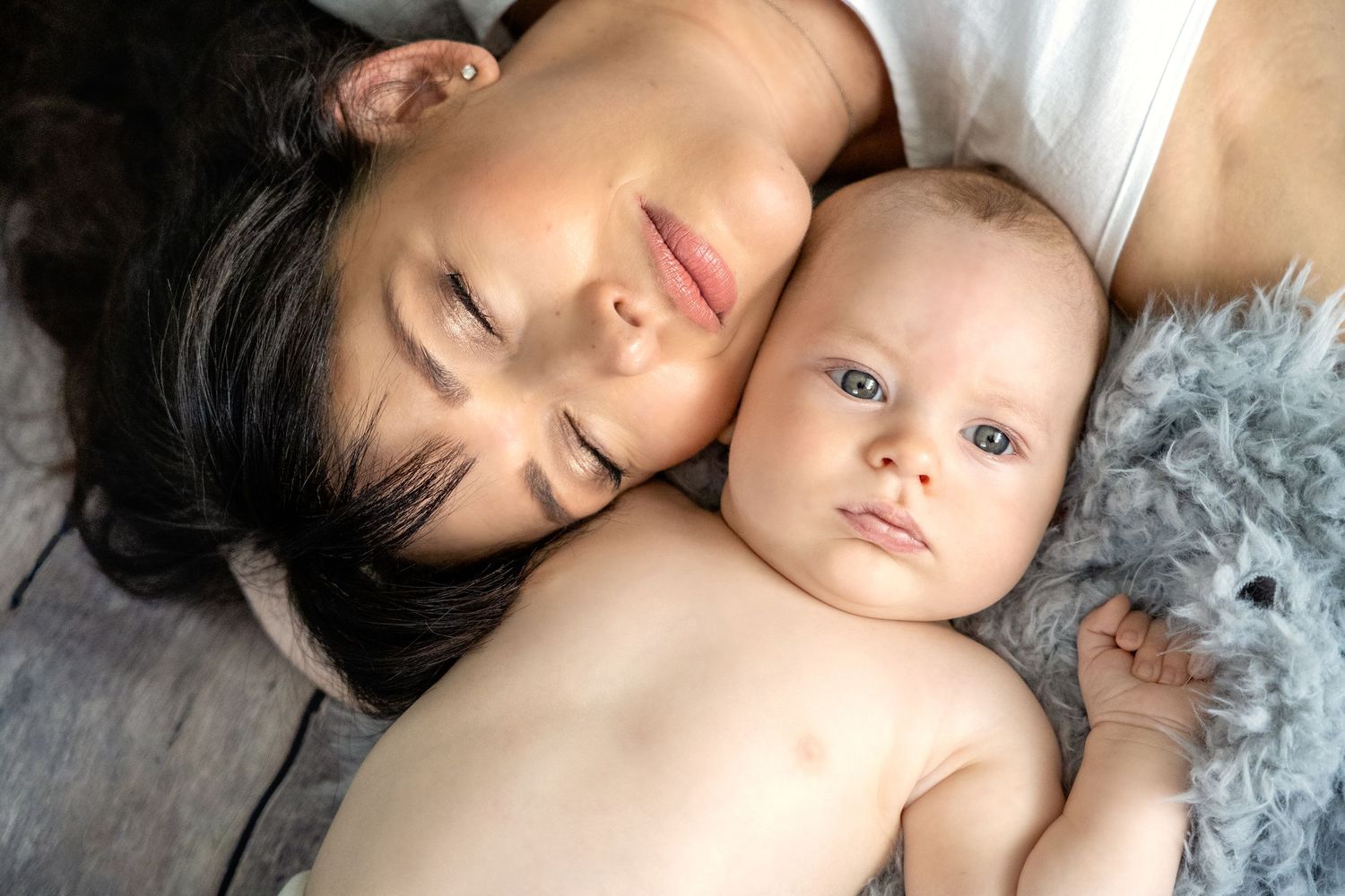 Newborn baby sleeping peacefully on soft white blanket in artistic portrait series.