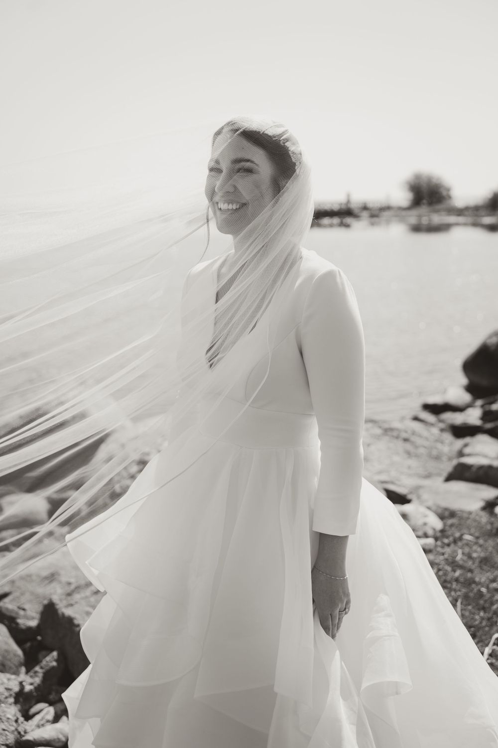 Black and white portrait of bride in classic dress with windswept veil.