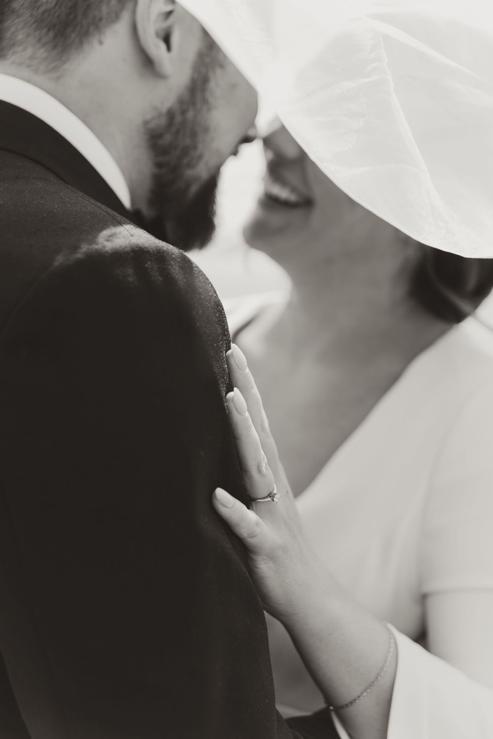 Close-up black and white shot of couple sharing tender moment under veil.