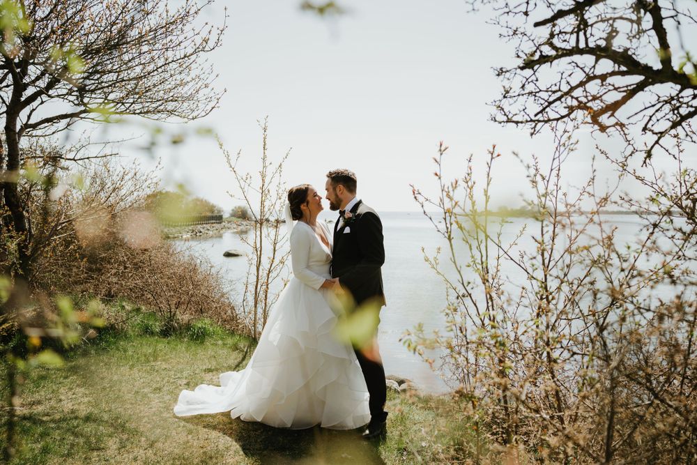 Wedding couple embracing on a scenic coastal path surrounded by spring foliage.