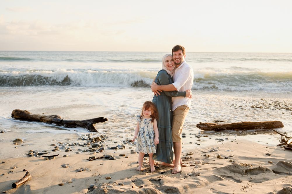 Punta Mita family photographer captures a family on the beach with driftwood and ocean waves during a beach family photo session.