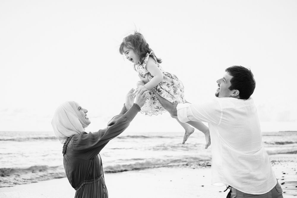 Sayulita family photographer captures a family playing on the beach with a child lifted high during a beach family photo session.