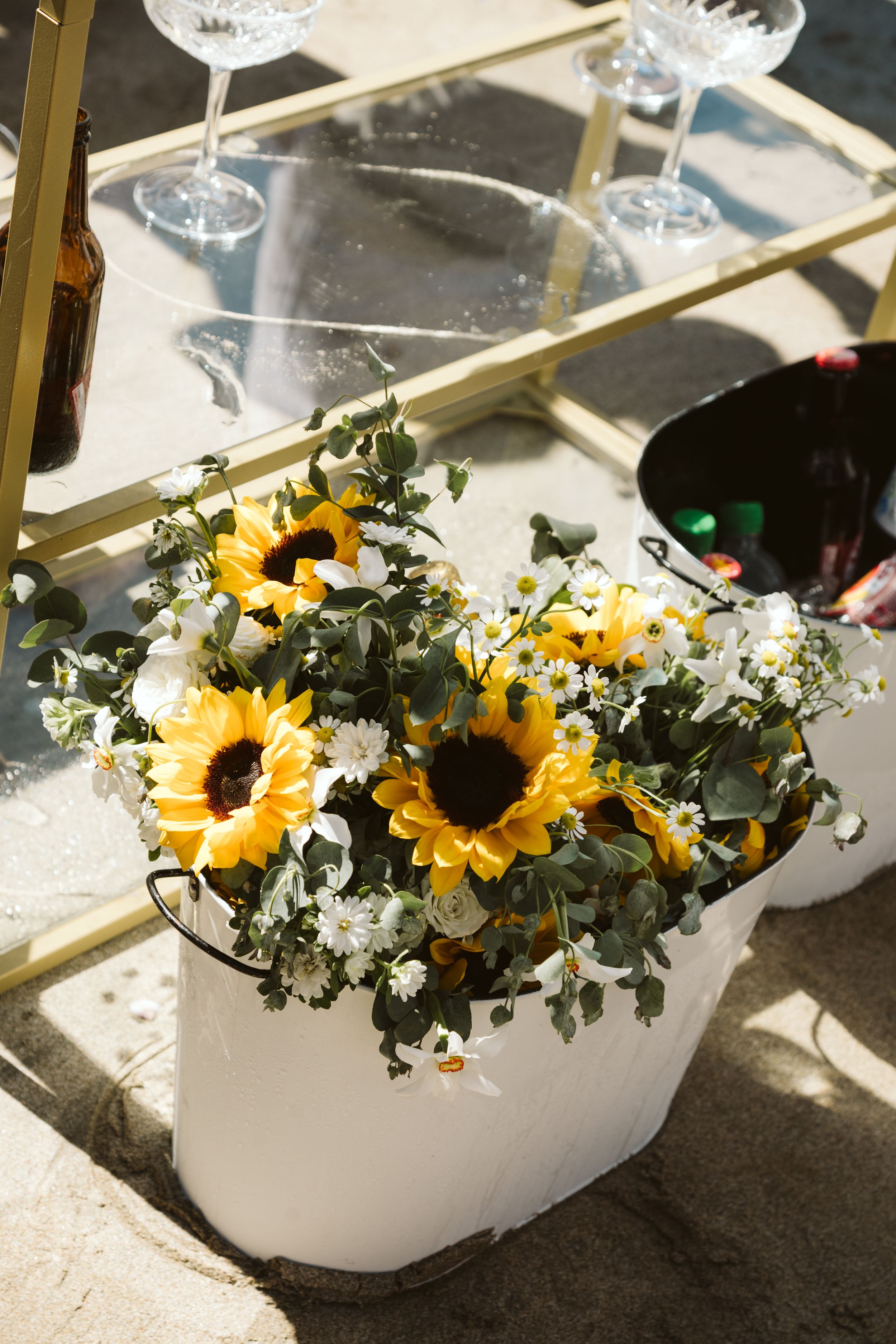 White ceramic vases filled with bright sunflowers and white daisies create an elegant floral display in natural light.