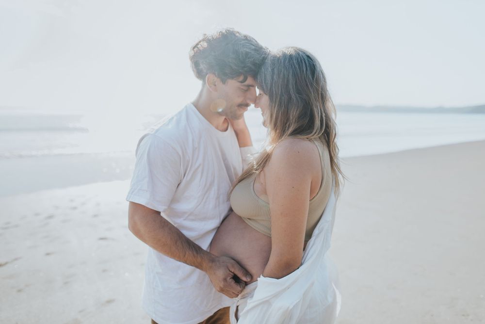 Romantic couple embracing on a sunlit beach in soft, dreamy lighting.