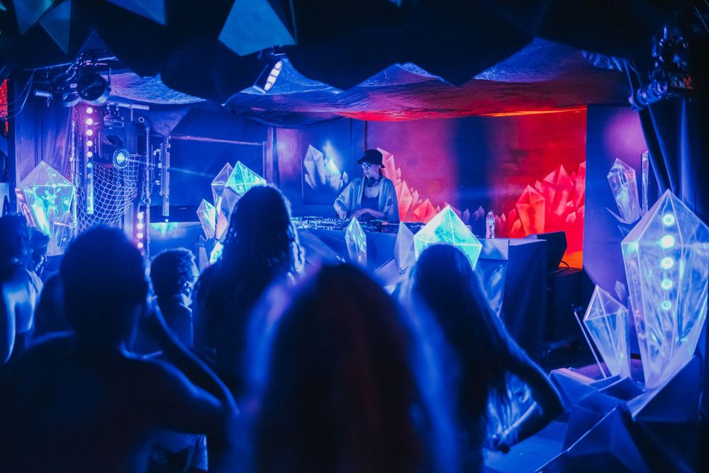 Concert crowd silhouettes against blue and red stage lighting at nightclub performance.