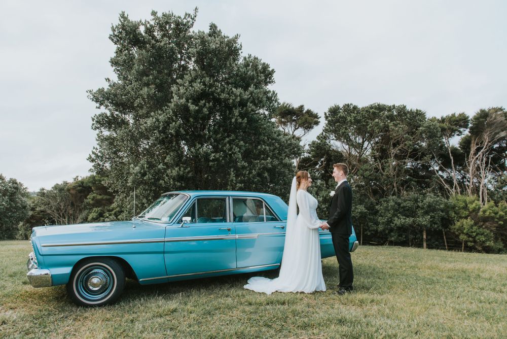 Classic turquoise car serves as backdrop for couple's outdoor portrait.