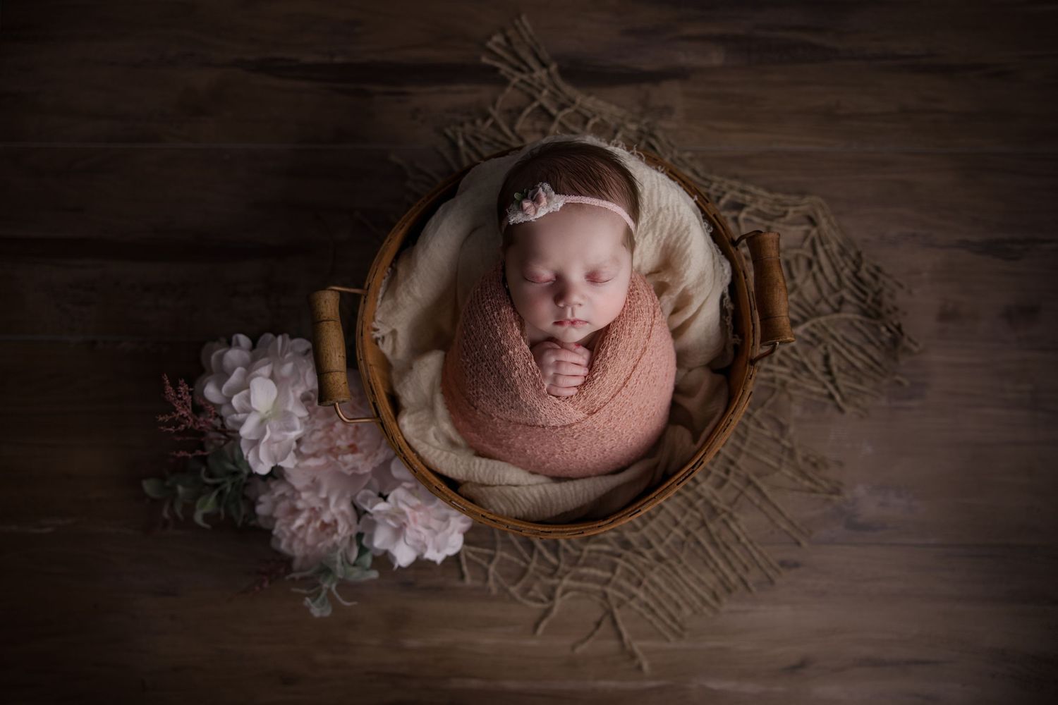 newborn baby swaddled in basket with flowers