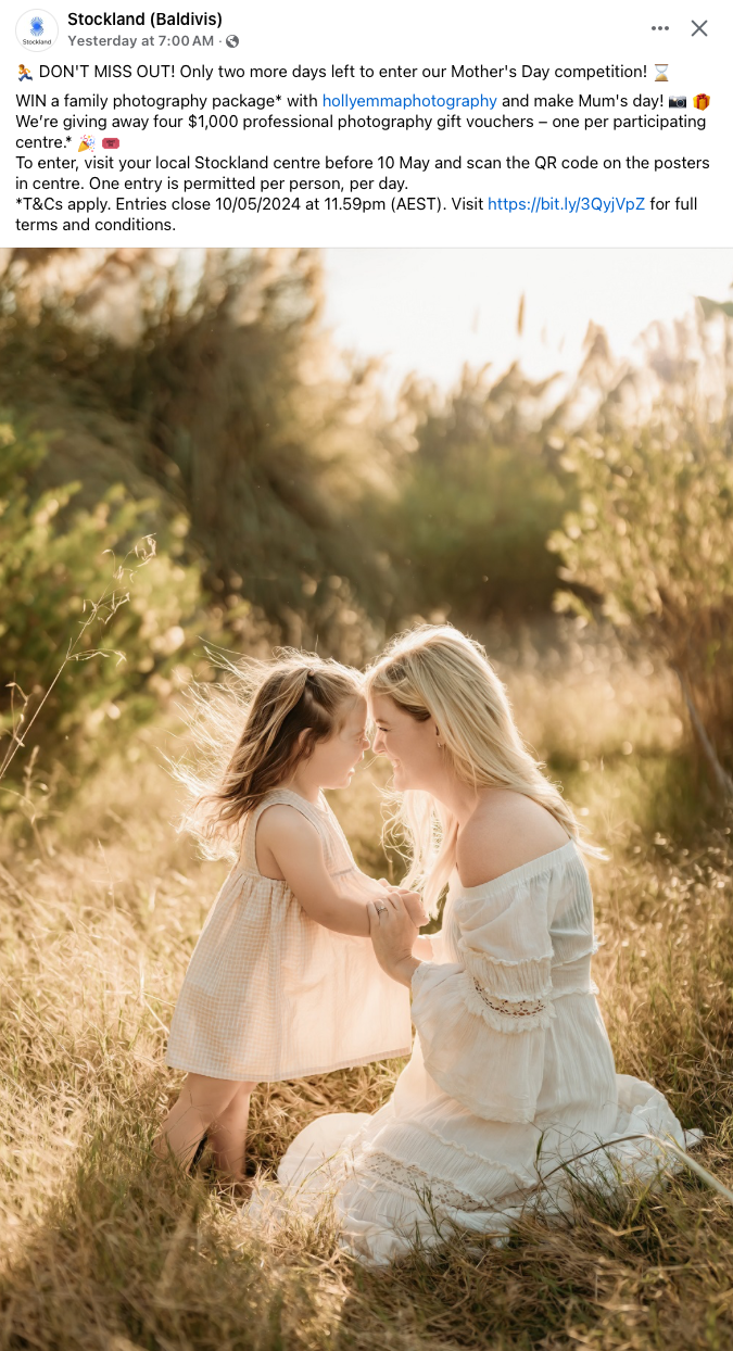 Backlit portrait of mother and child in white dresses sitting in a golden sunlit field.