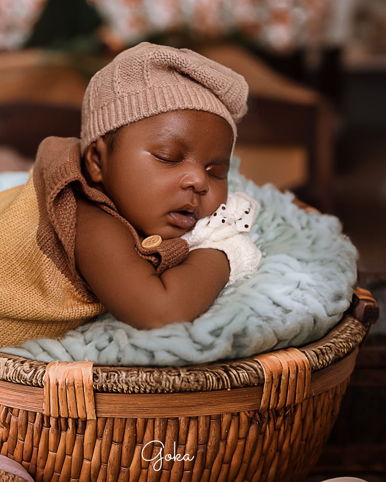 Peaceful sleeping baby in brown knit hat rests in woven basket on soft blanket.