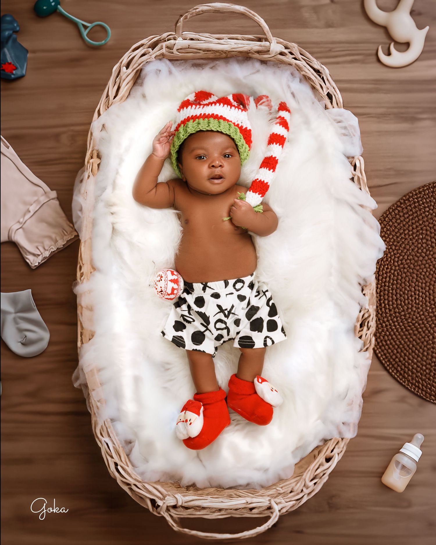 Holiday themed newborn photo with striped hat and cow print diaper in wicker basket.