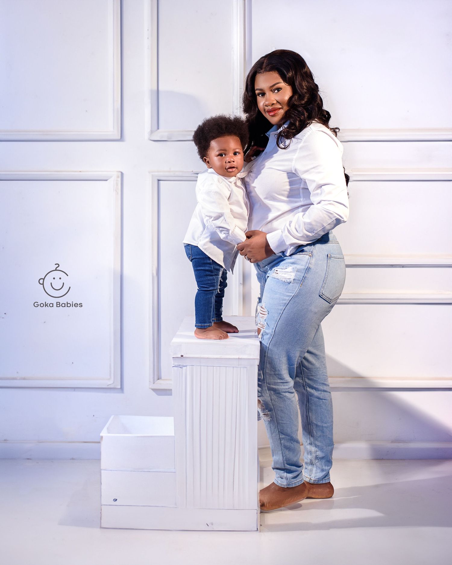 Family portrait against white wall background with decorative white steps.