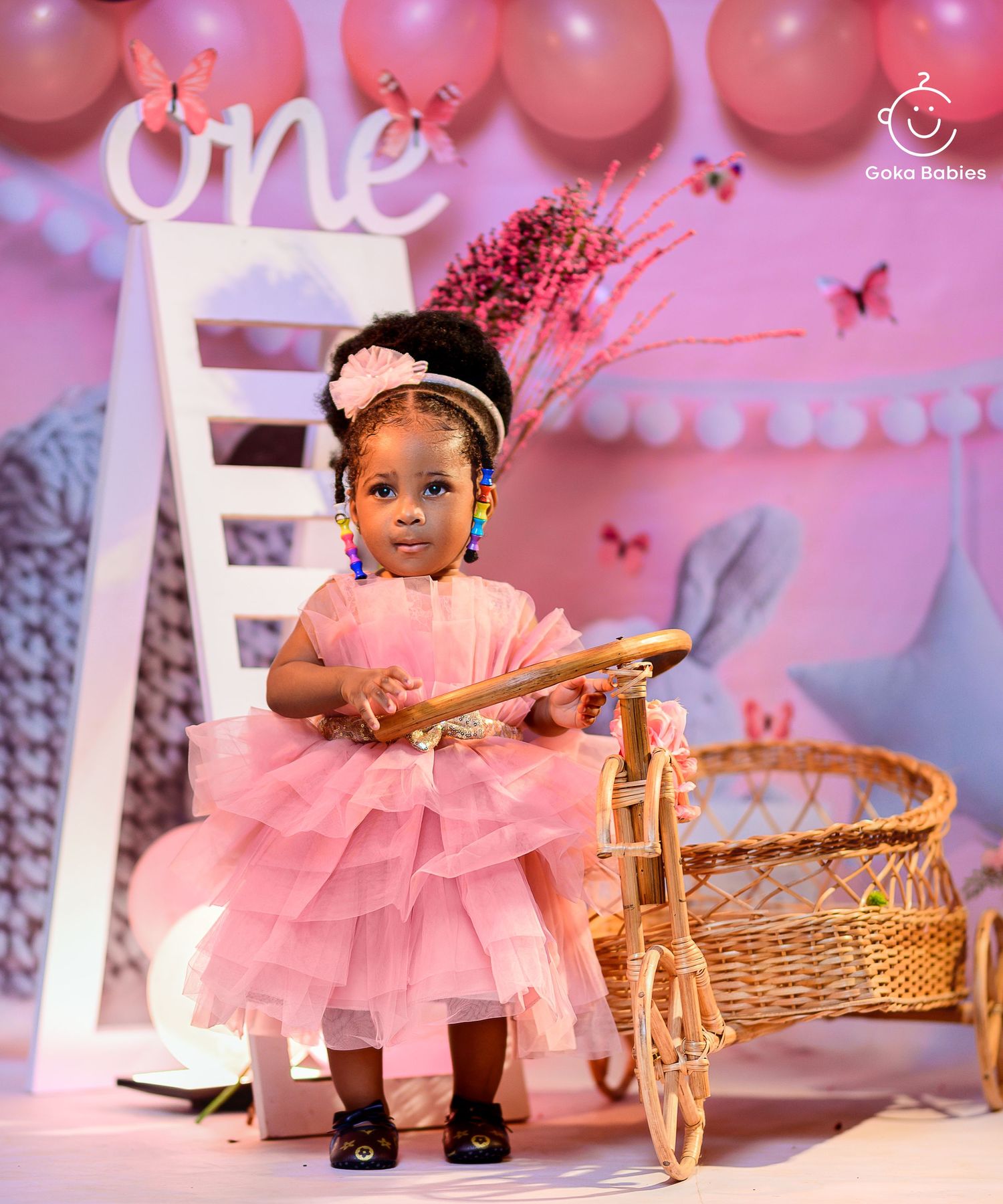 Pink tulle party dress and white decor create a magical first birthday setting with balloons and butterflies.