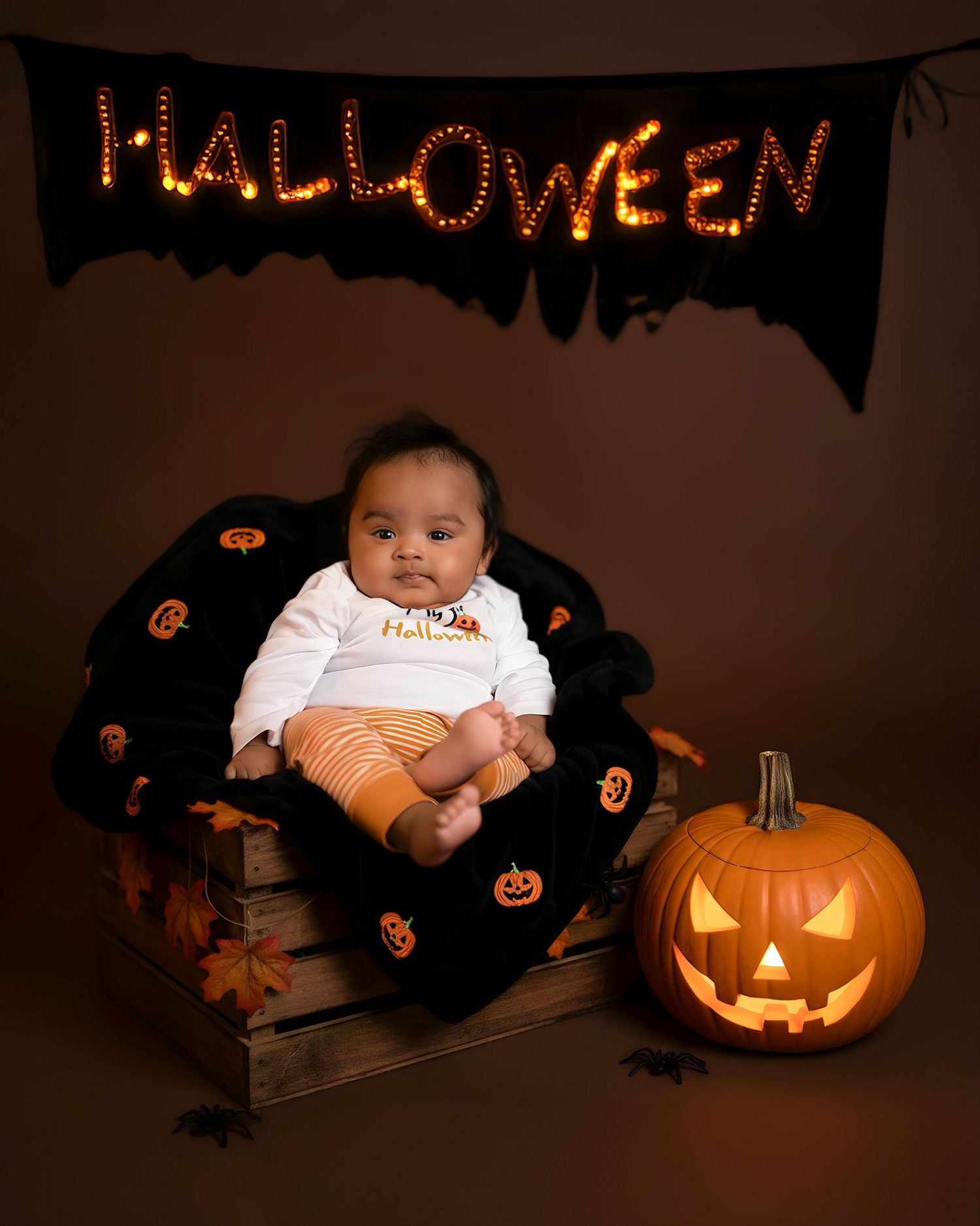 A series of Halloween-themed baby photos with a glowing jack-o'-lantern pumpkin against a dark background.