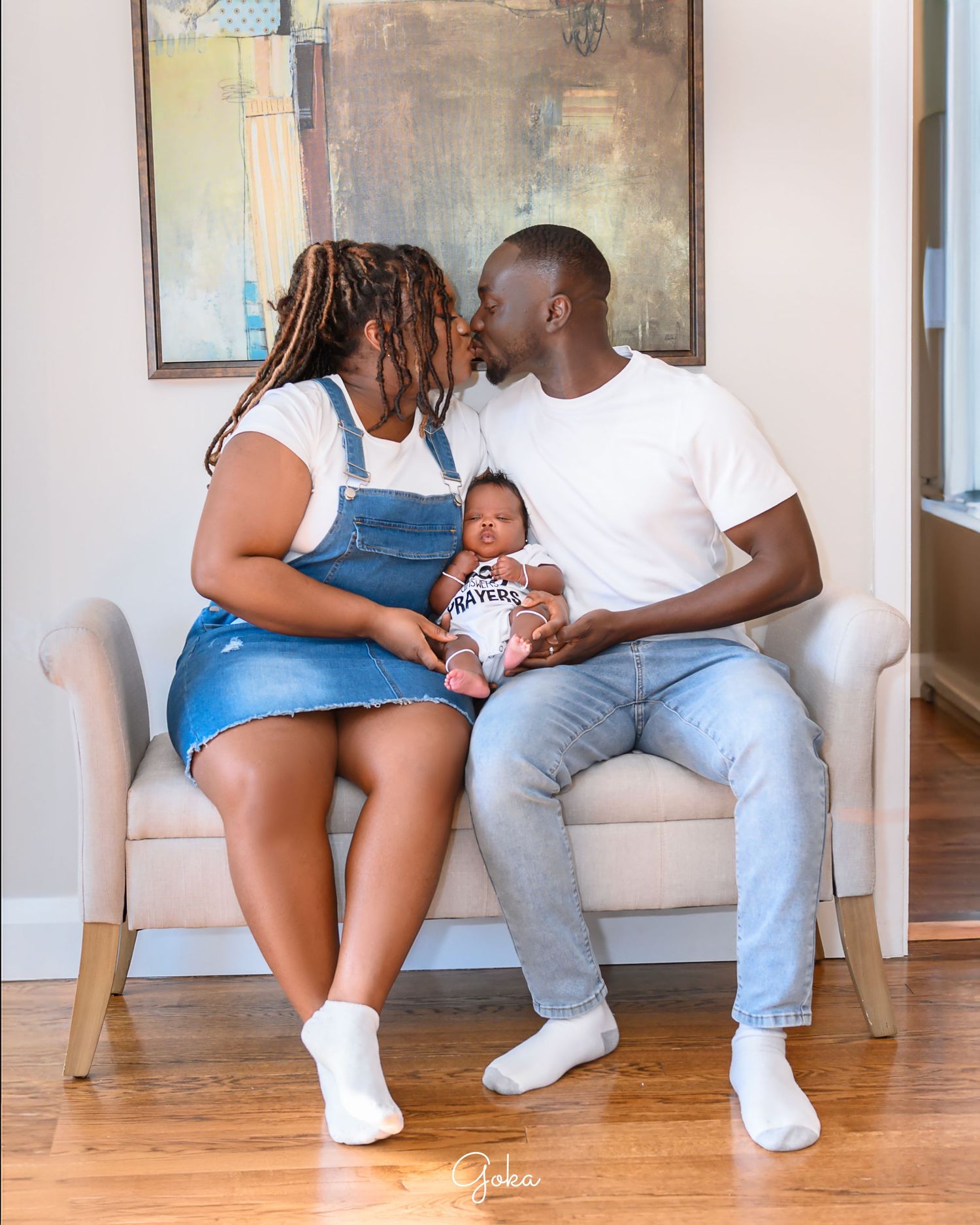 Family sharing intimate moment on white couch with artwork in background.