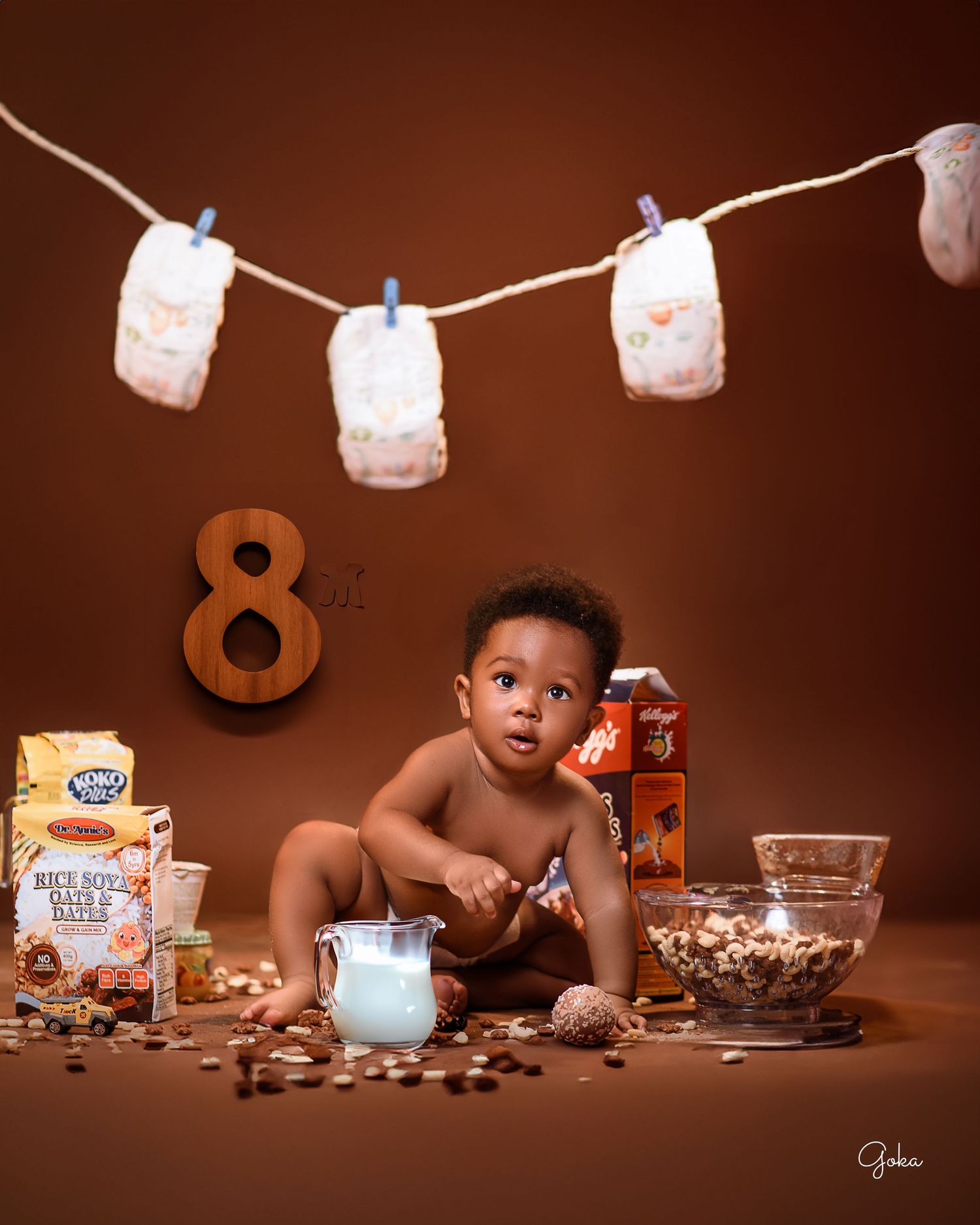 Candid breakfast scene with cereal, milk, and decorative hanging diapers against brown background.