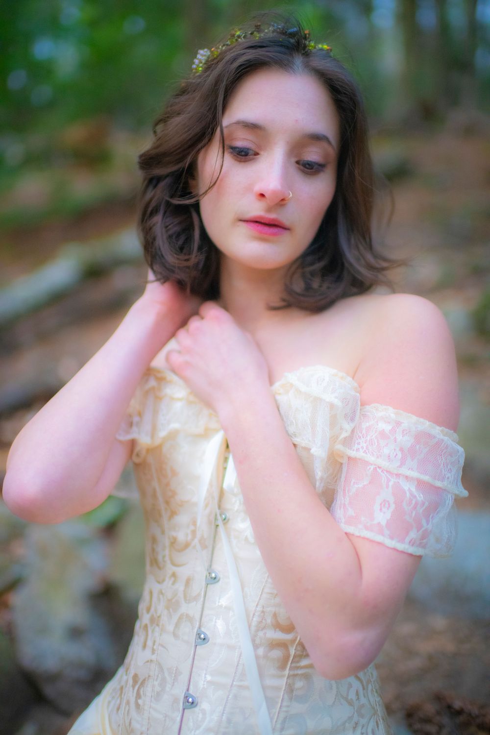 Soft-focus portrait featuring delicate lace corset and ethereal lighting in forest setting.