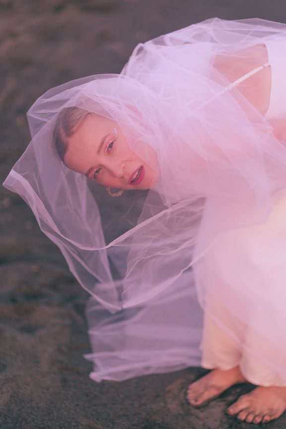 Bridal portrait of a girl draped in a light pink wedding veil