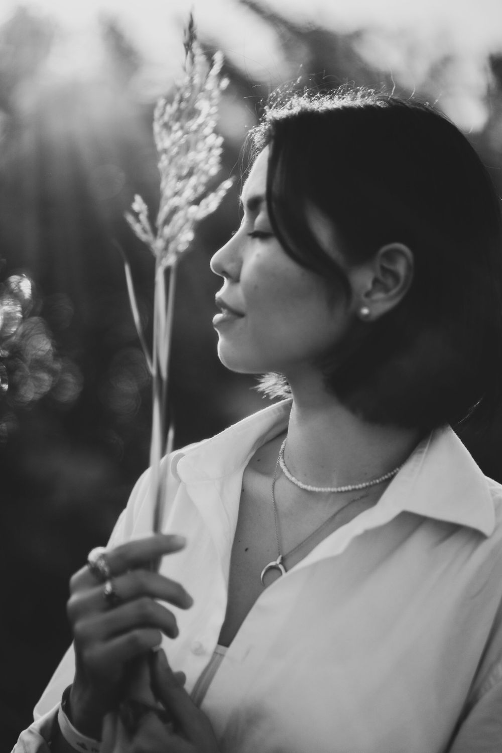 black and white portrait of a woman holding dried stem of grass