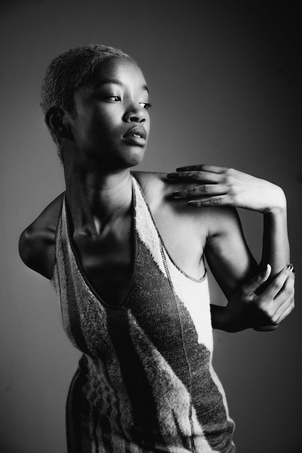 A beautiful short-haired woman posing in a studio, captured in black and white photography