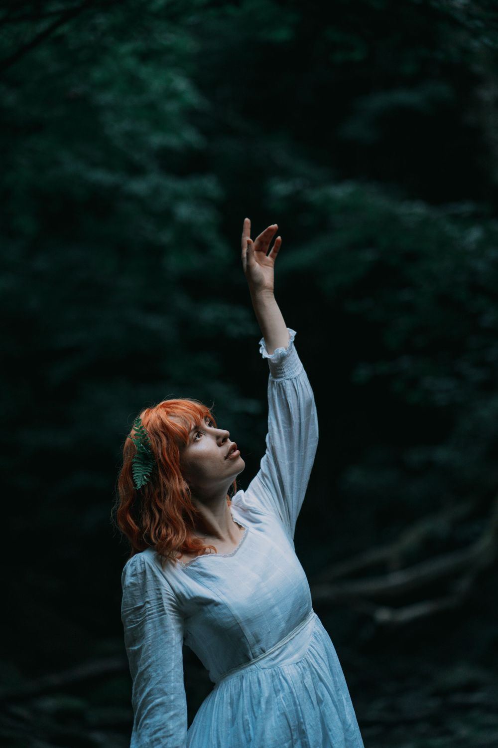 Whimsical fairy portrait of a woman in a white dress amidst a lush green forest