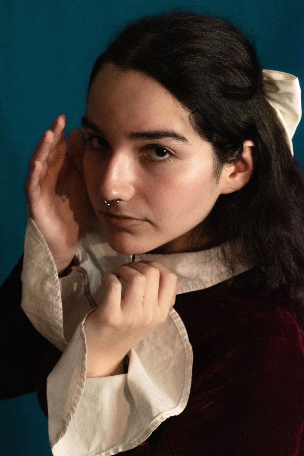 Portrait in vintage style with ruffled collar against teal background.