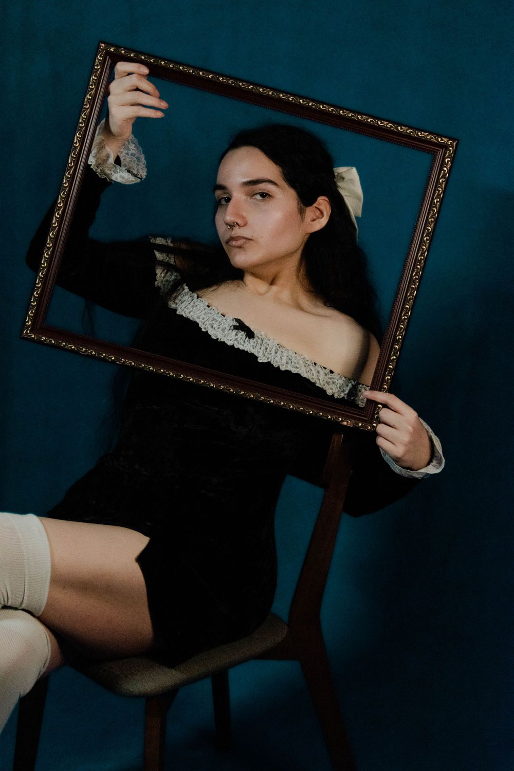 Moody portrait with vintage frame against dark teal background.