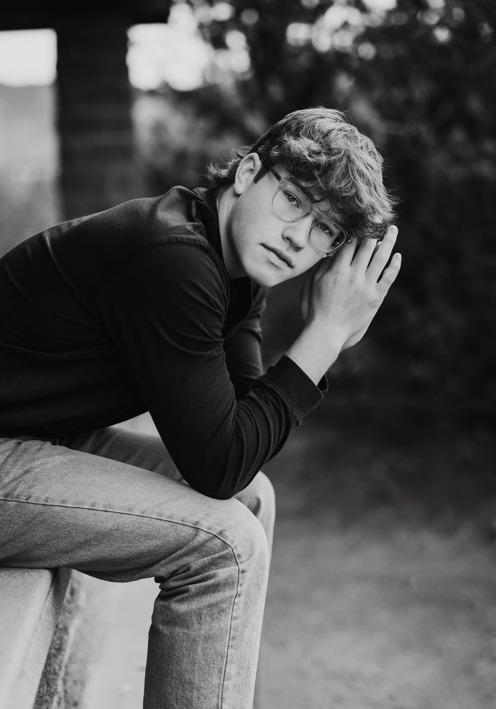 Black and white portrait of person in dark clothing posing thoughtfully.