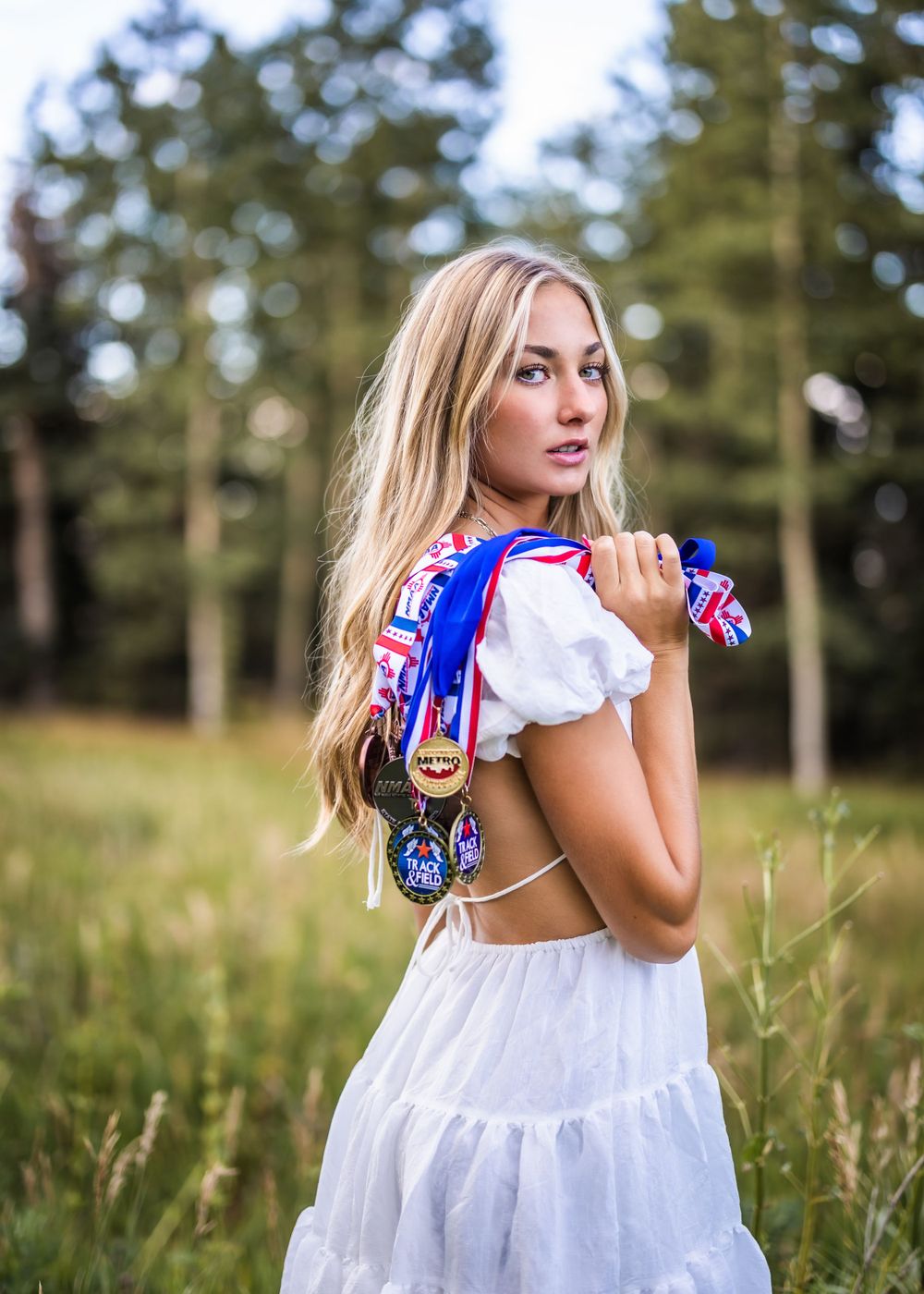 A summery portrait in a white dress with patriotic ribbons in a meadow setting.