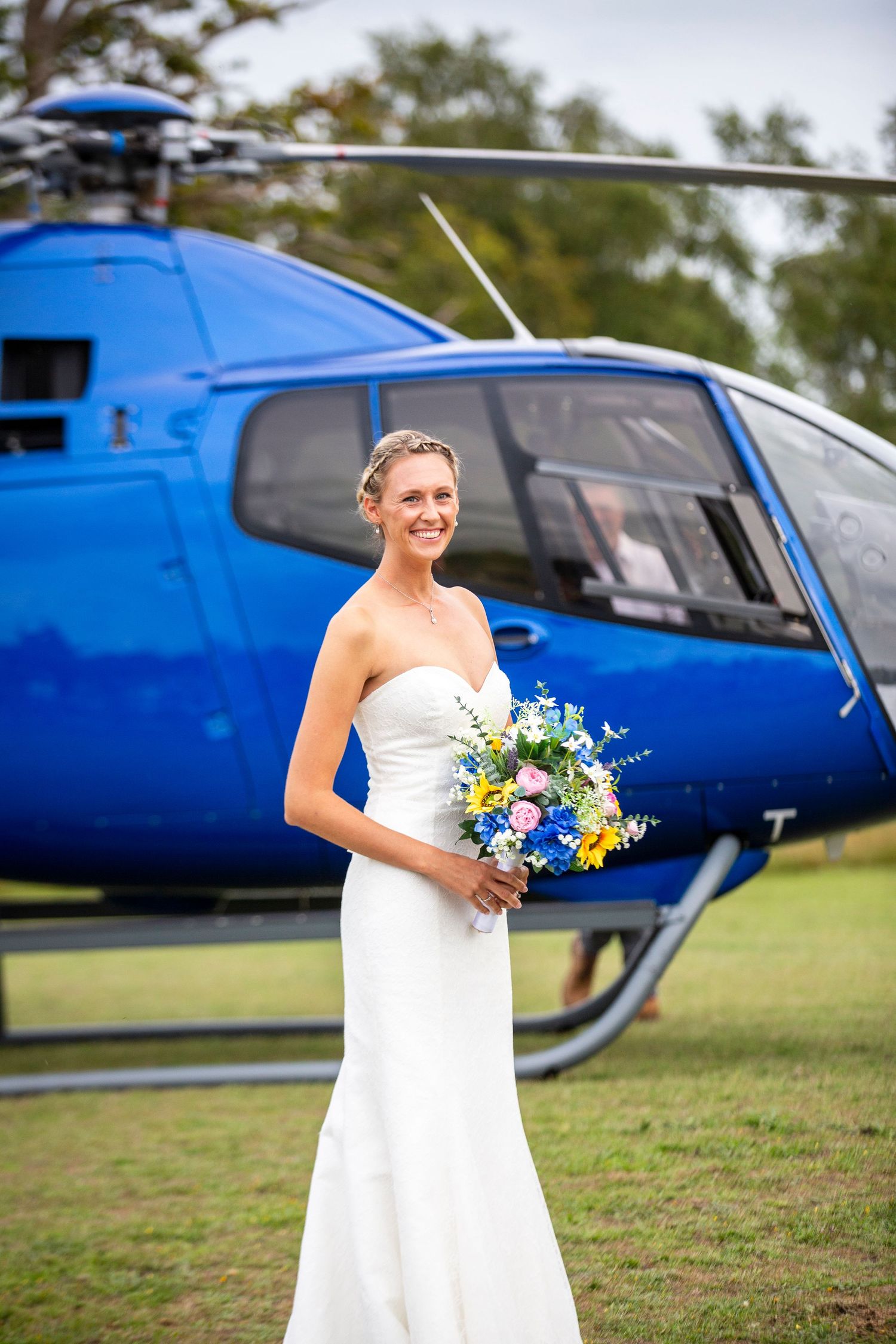 Wedding photos with bright blue helicopter backdrop in outdoor setting.