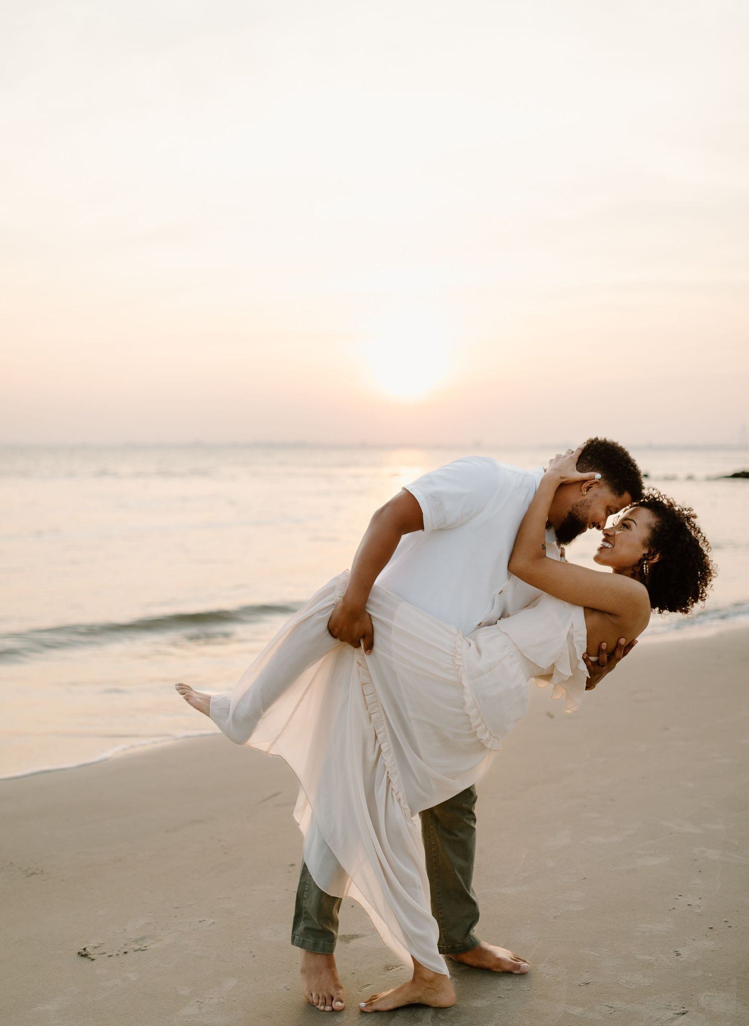 Romantic beach wedding photo with couple embracing during sunset.