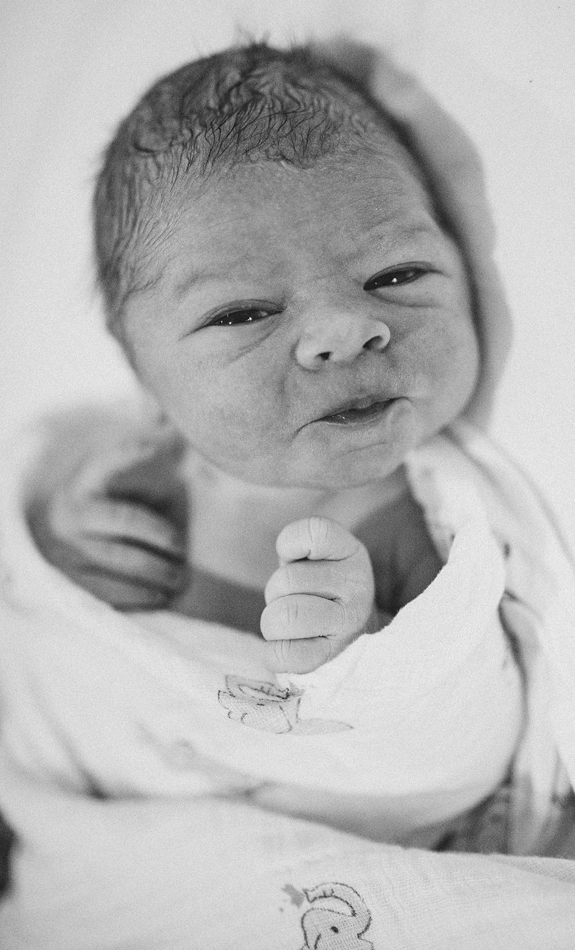 Close-up black and white portrait of a newborn baby making an expression.