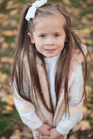 Little girl looking up at camera, autumnal leaves in the background